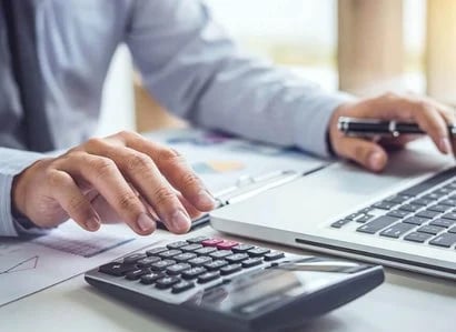 Employee working on computer with calculator