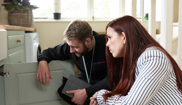 Drain Doctor engineer and customer looking under sink